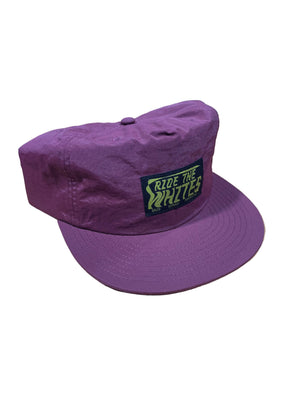 Purple cap with 'Ride the Whites' logo on a wooden surface