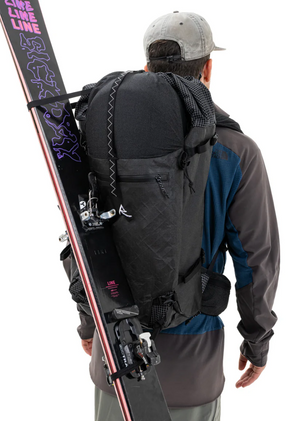 Person carrying a backpack with skis attached on a white background
