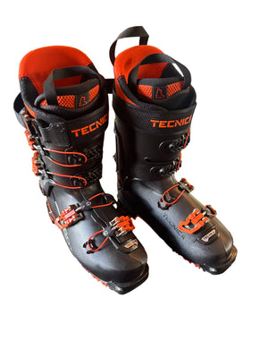 Pair of black and orange Tecnica ski boots on a white surface.