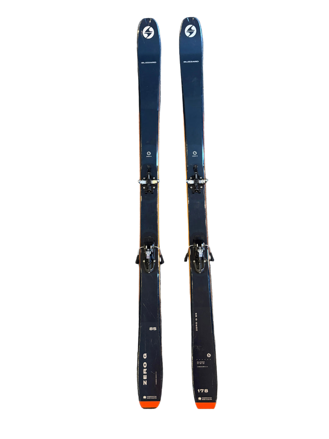 Two pairs of skis with bindings on a gray tiled floor